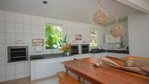 Una cocina moderna con baldosas blancas, una mesa de comedor de madera y esferas decorativas colgantes.