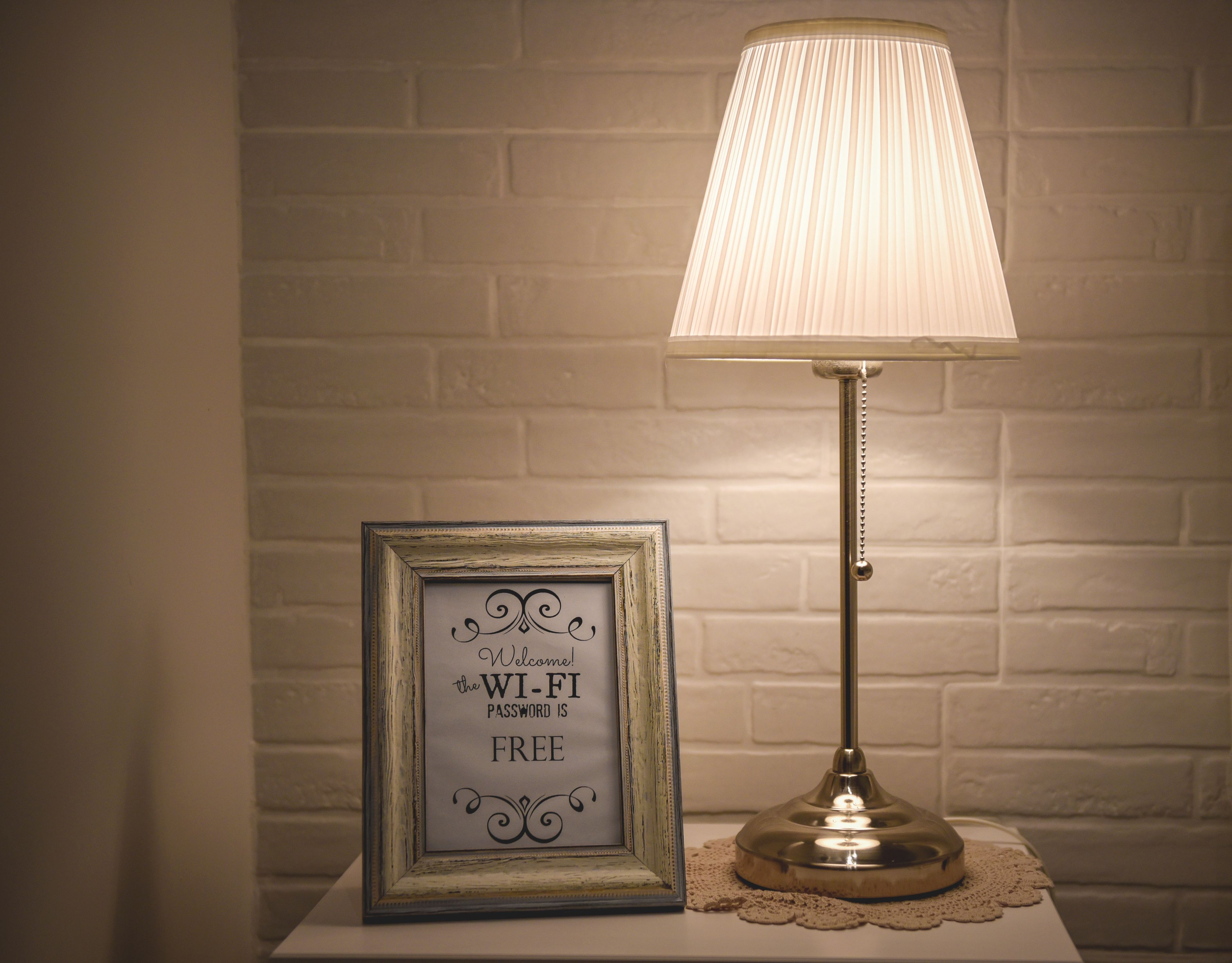 A framed sign with a Wi-Fi password on a table next to a lamp.