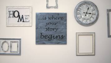 Eine Wand mit verschiedenen gerahmten Gegenständen, darunter eine Uhr, ein Schild mit dem Wort 'HOME' und mehrere leere Bilderrahmen.