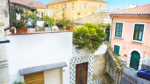 A narrow street with buildings on either side, a blue car parked on the right, and a metal gate in the foreground. - Elegant B&B Il Vicolo storico (Salerno)