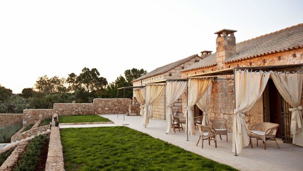 A stone building with outdoor seating and a well-maintained lawn. - Masseria Cisternella (Alliste)