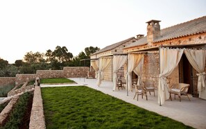 A stone building with outdoor seating and a well-maintained lawn. - Masseria Cisternella (Alliste)