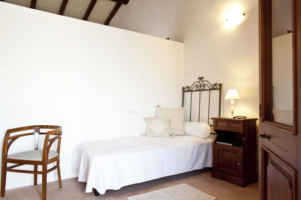 Ein Schlafzimmer mit Bett, Stuhl, Nachttisch und Spiegel.