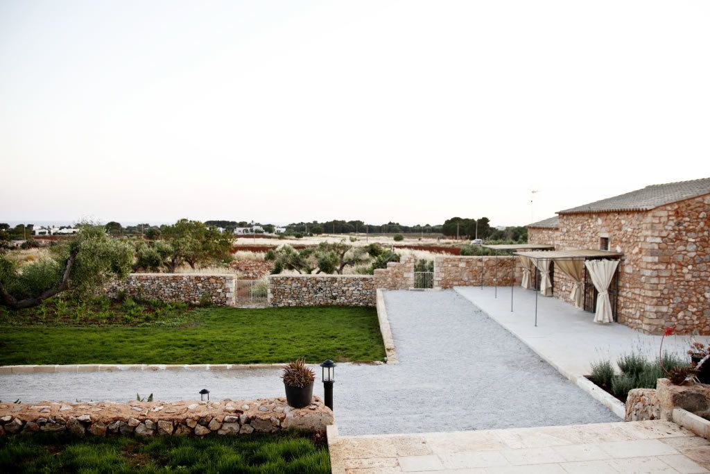 A stone building with a paved patio and a grassy area.