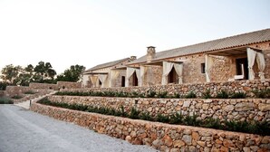 A stone building with multiple rooms, a stone retaining wall, and a gravel path. - Masseria Cisternella (Alliste)