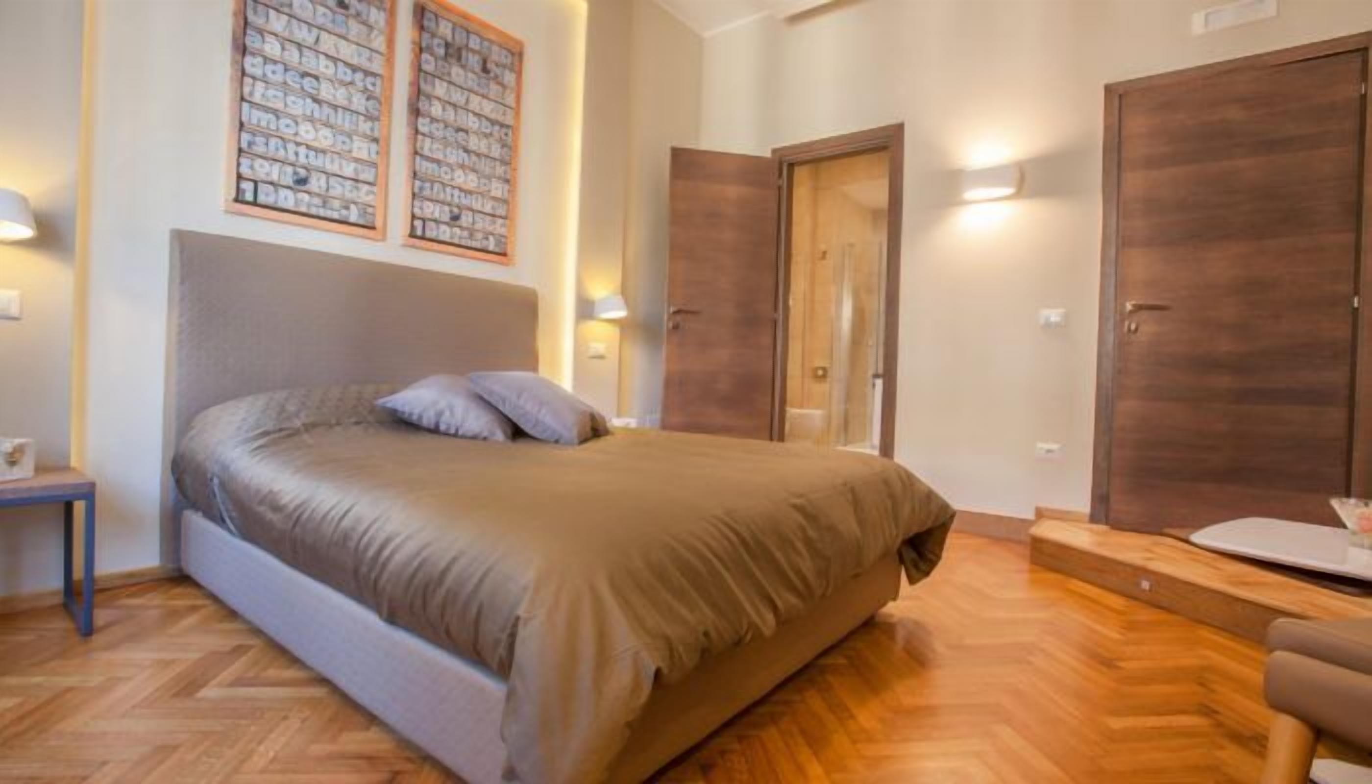 A bedroom with a bed, a nightstand, a dresser, and a mirror.
