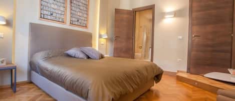 A bedroom with a bed, a nightstand, a dresser, and a mirror.