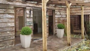 A courtyard with wooden pergolas, stone flooring, and potted plants. - Apartamentos Charm Centro Gramado (Gramado)