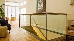 A modern interior with a staircase, a glass railing, and a large window. - Apartamentos Charm Centro Gramado (Gramado)
