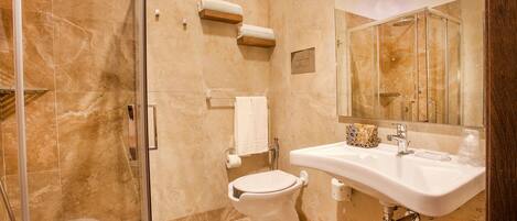 A modern bathroom with a glass-enclosed shower, a white sink, and a marble-tiled floor.