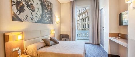 A hotel room with a large bed, a nightstand, a wall clock, a window with a view of buildings, and a TV mounted on the wall.