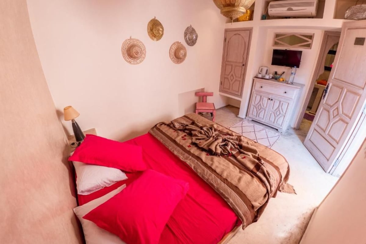 Quarto com cama, guarda-roupa, televisão e objetos decorativos na parede.