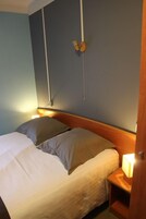 Una habitación de hotel con una cama, una mesita de noche con una lámpara y una lámpara de pared.