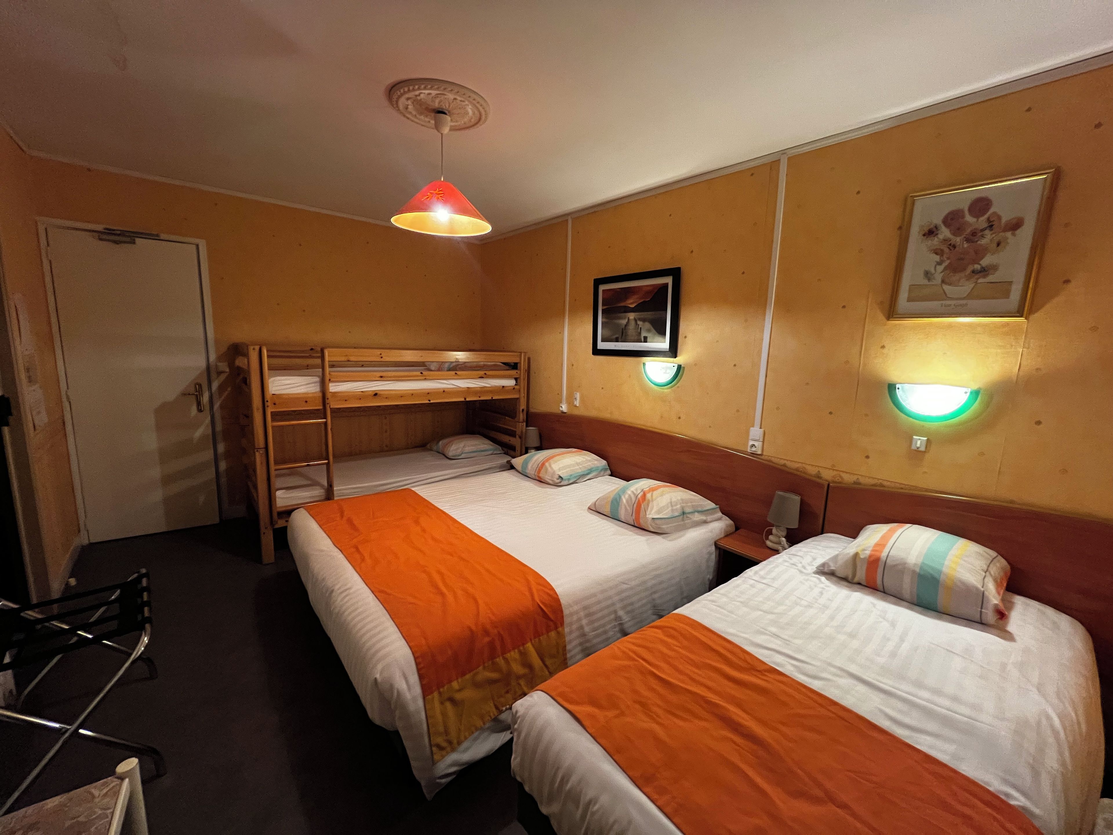 Habitación de hotel con literas, un escritorio, una silla y una cama con almohada a rayas.