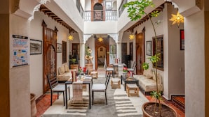 A spacious courtyard with a central seating area, surrounded by arches and potted plants. - Riad Sun of Kech (Marrakech)