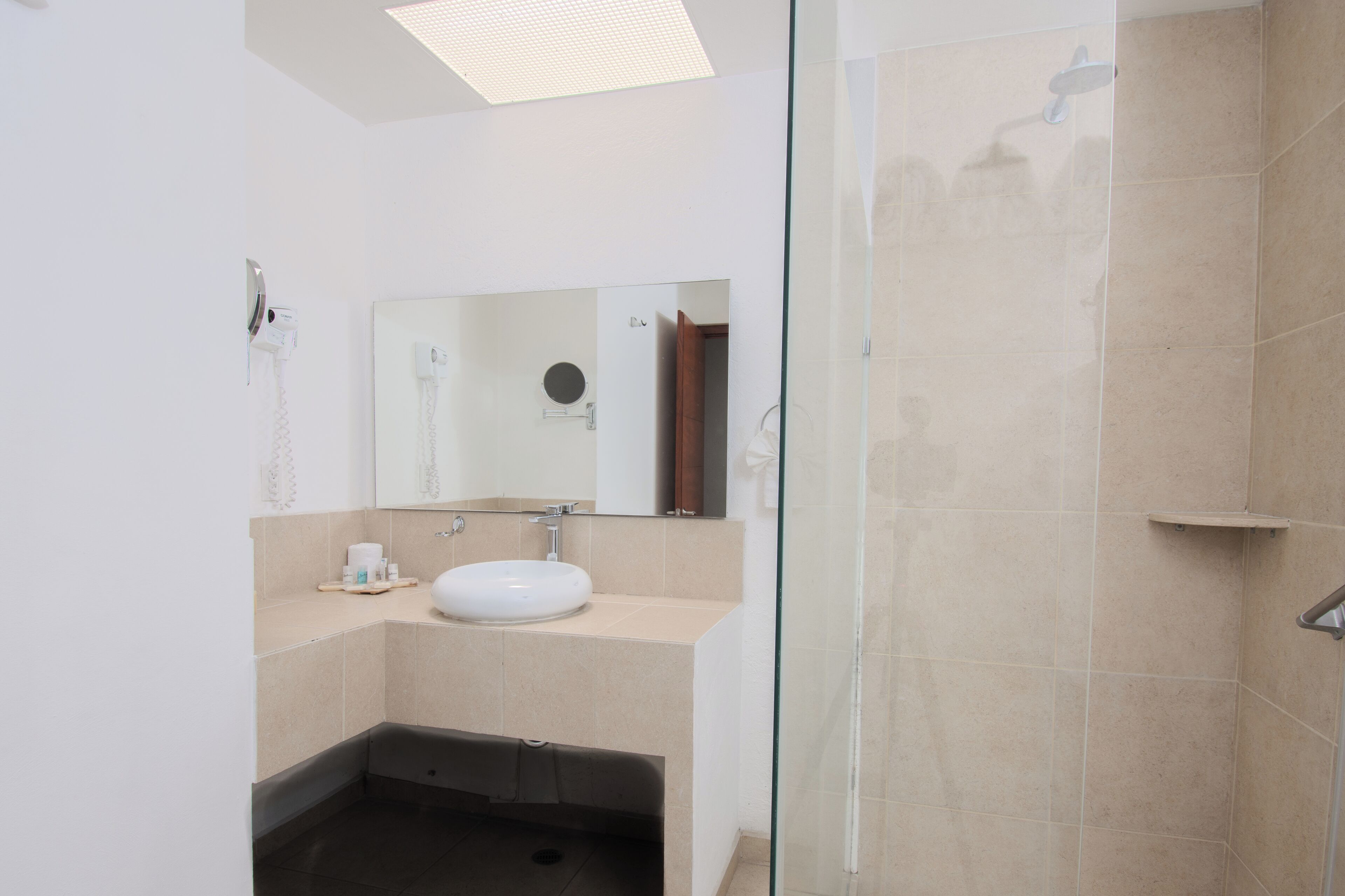 A modern bathroom with a glass shower enclosure, a white sink, and a mirror above it.