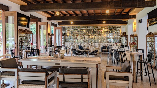 Un amplio bar con vigas de madera, diversas opciones de asientos y una barra bien surtida.