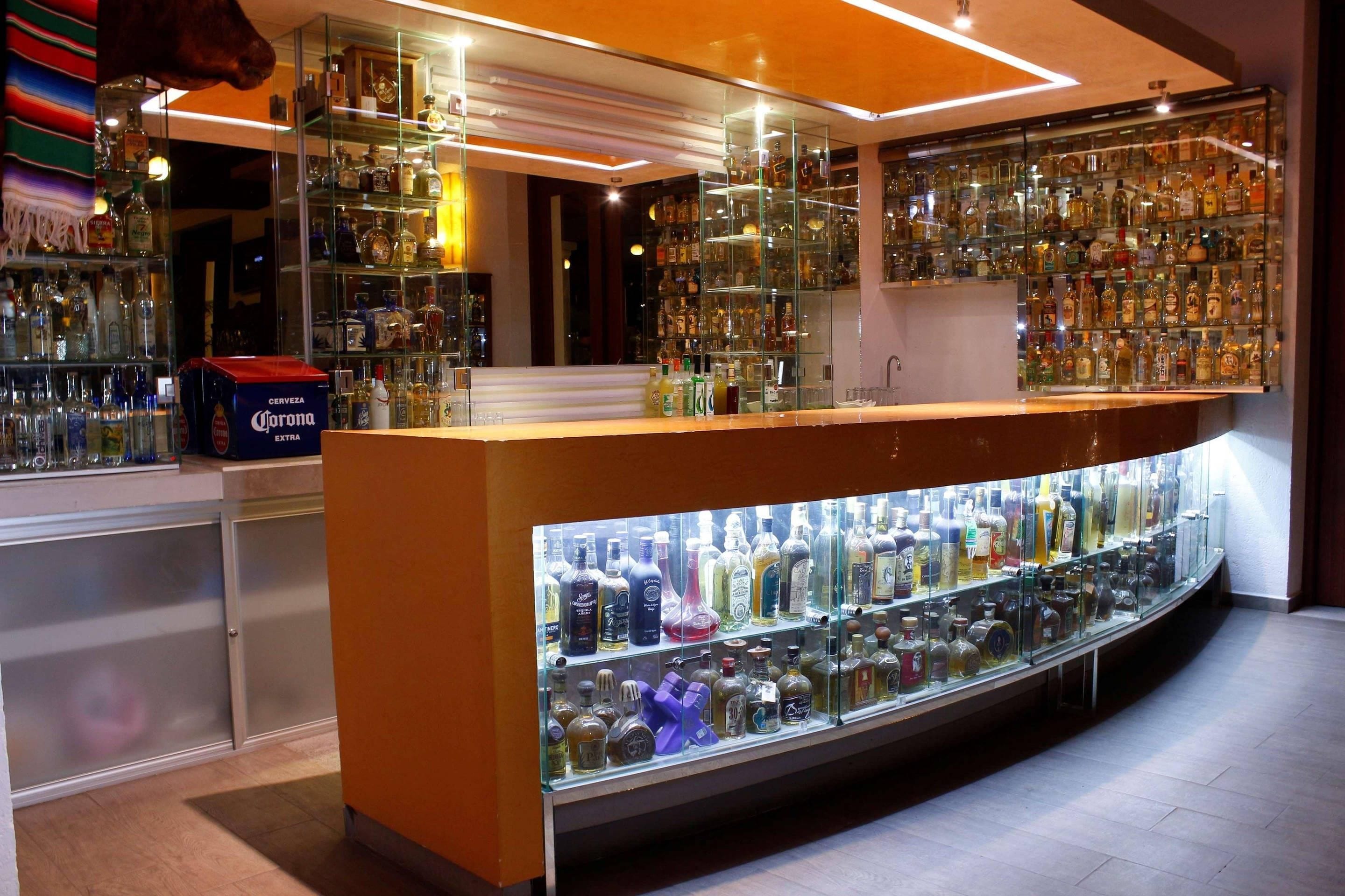 A bar area with a glass display case filled with various liquor bottles.