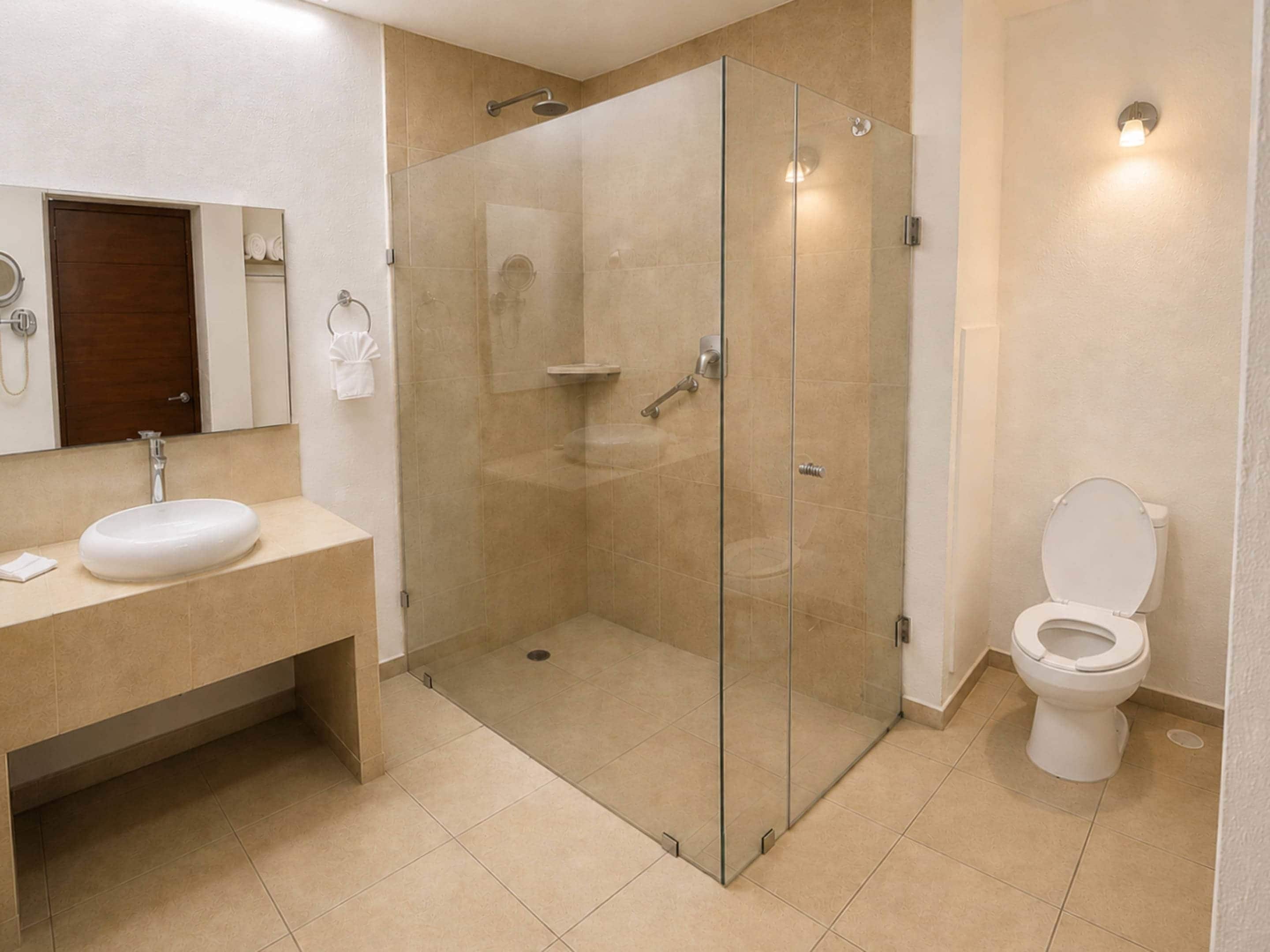 A modern bathroom with a glass-enclosed shower, a sink, a toilet, and a mirror.