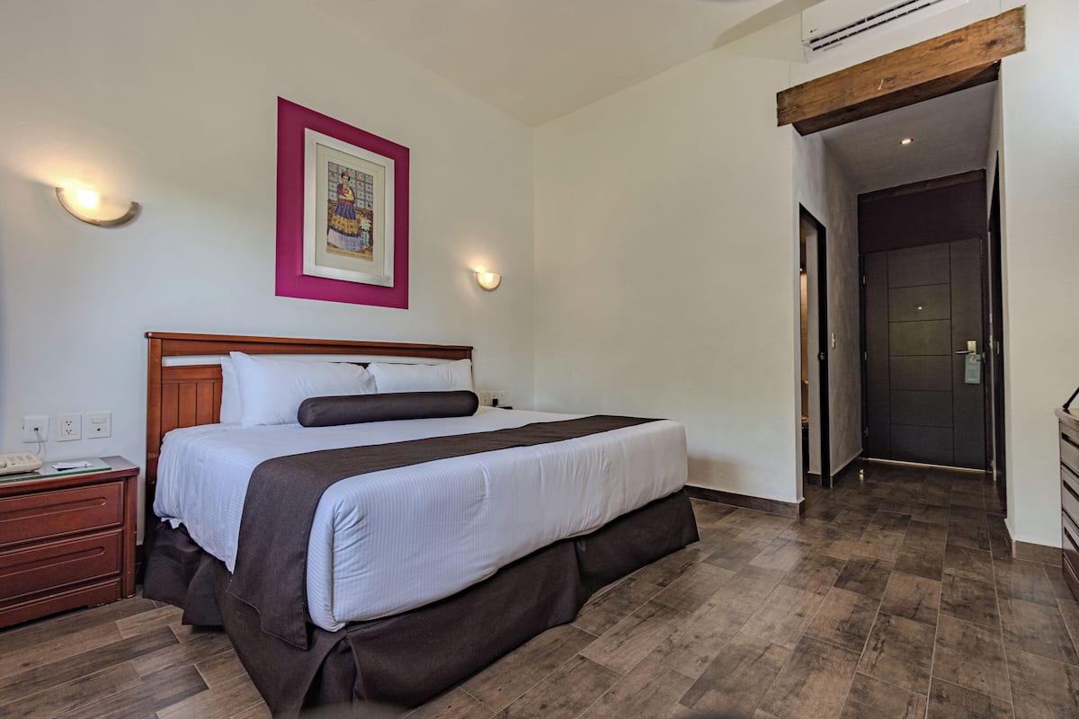 Un lit bien fait, avec une tête de lit en bois, une table de chevet avec une lampe et un tableau encadré accroché au mur.