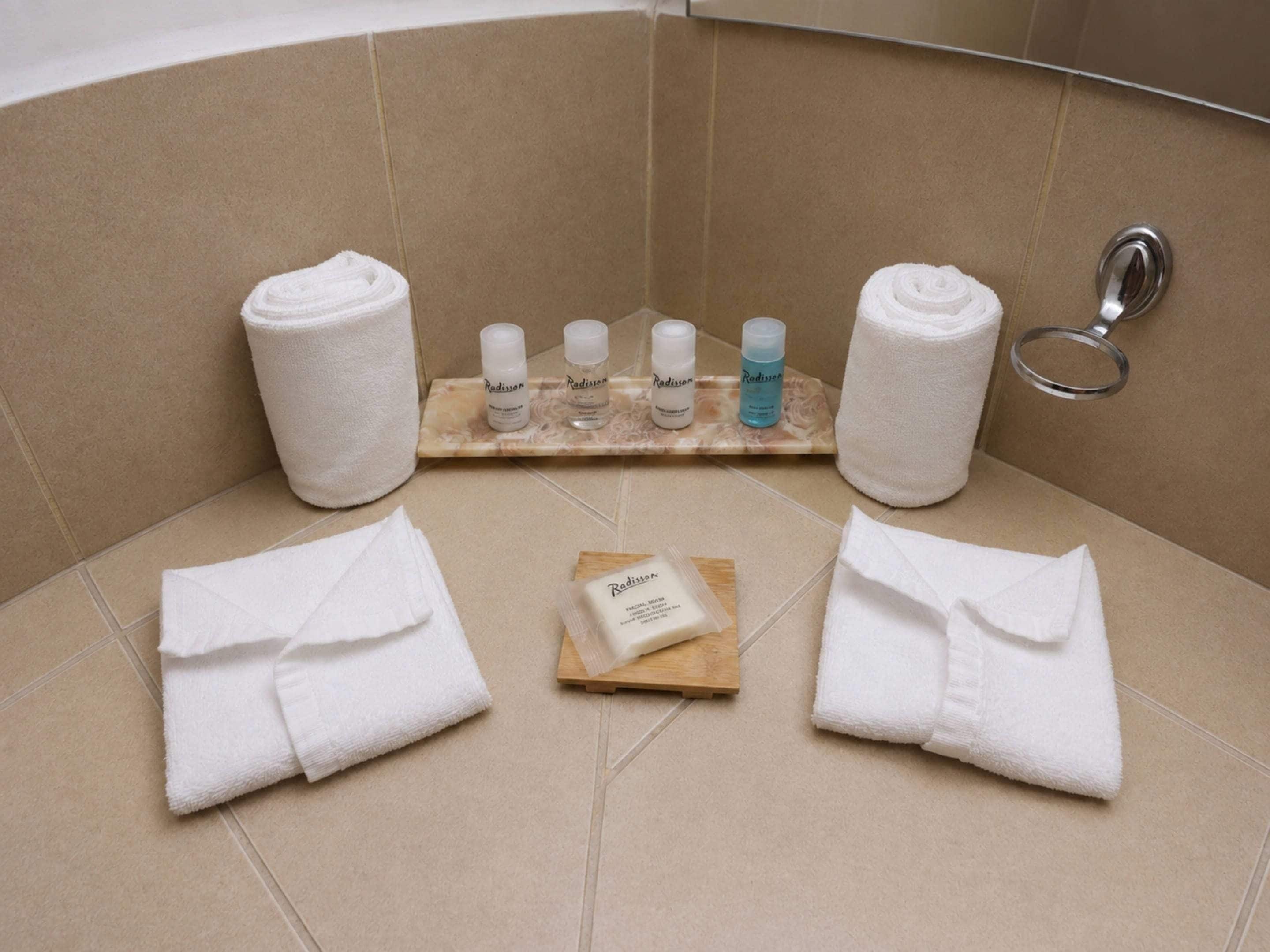 Un baño con toallas, un secador de manos y artículos de aseo en un estante.