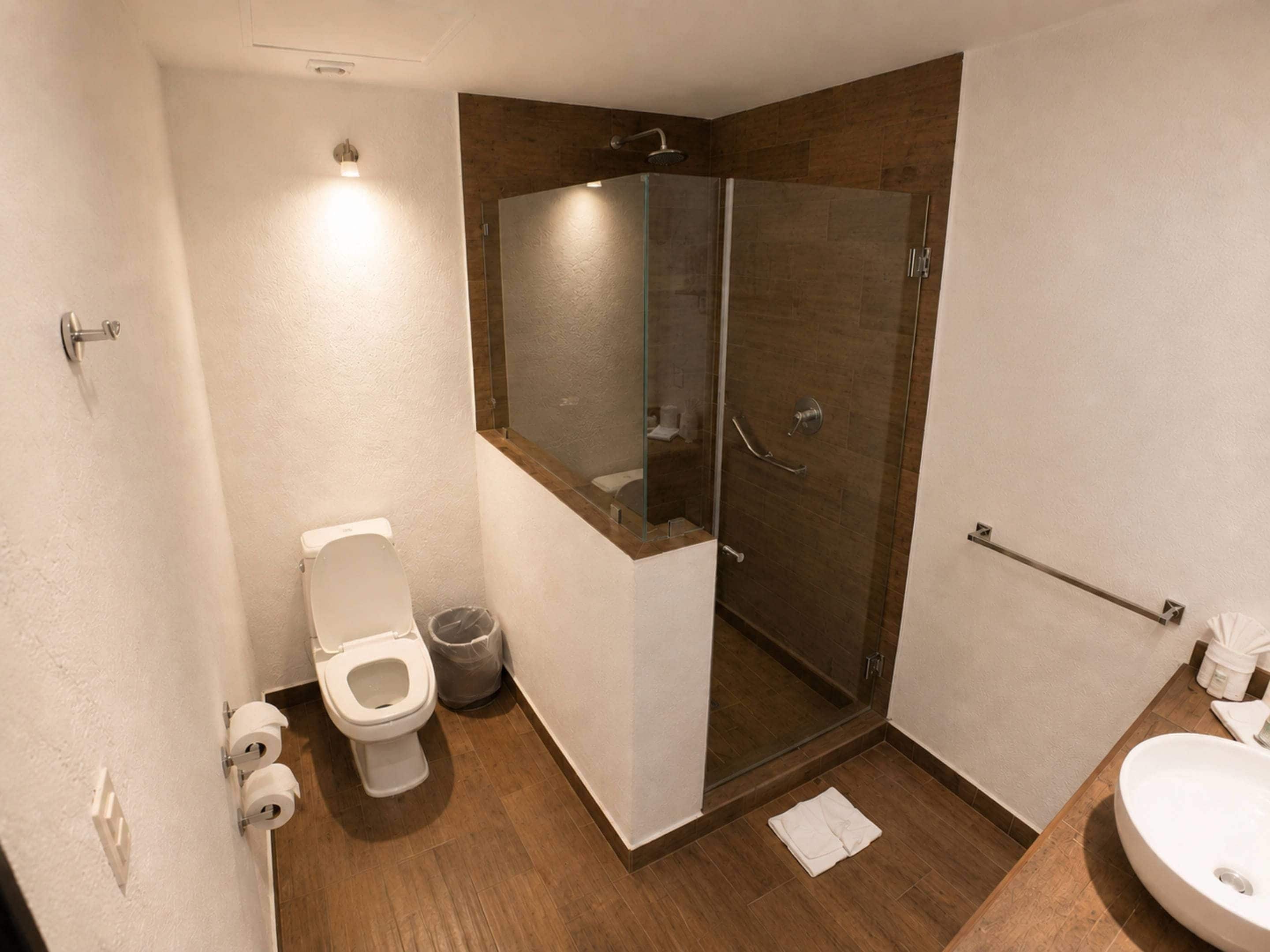 A modern bathroom with a toilet, a glass-enclosed shower, and a sink.