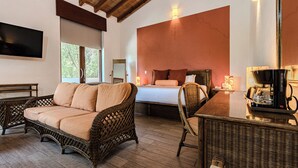 Una habitación amplia con una cama grande, muebles de mimbre, una cafetera y un televisor de pantalla plana.