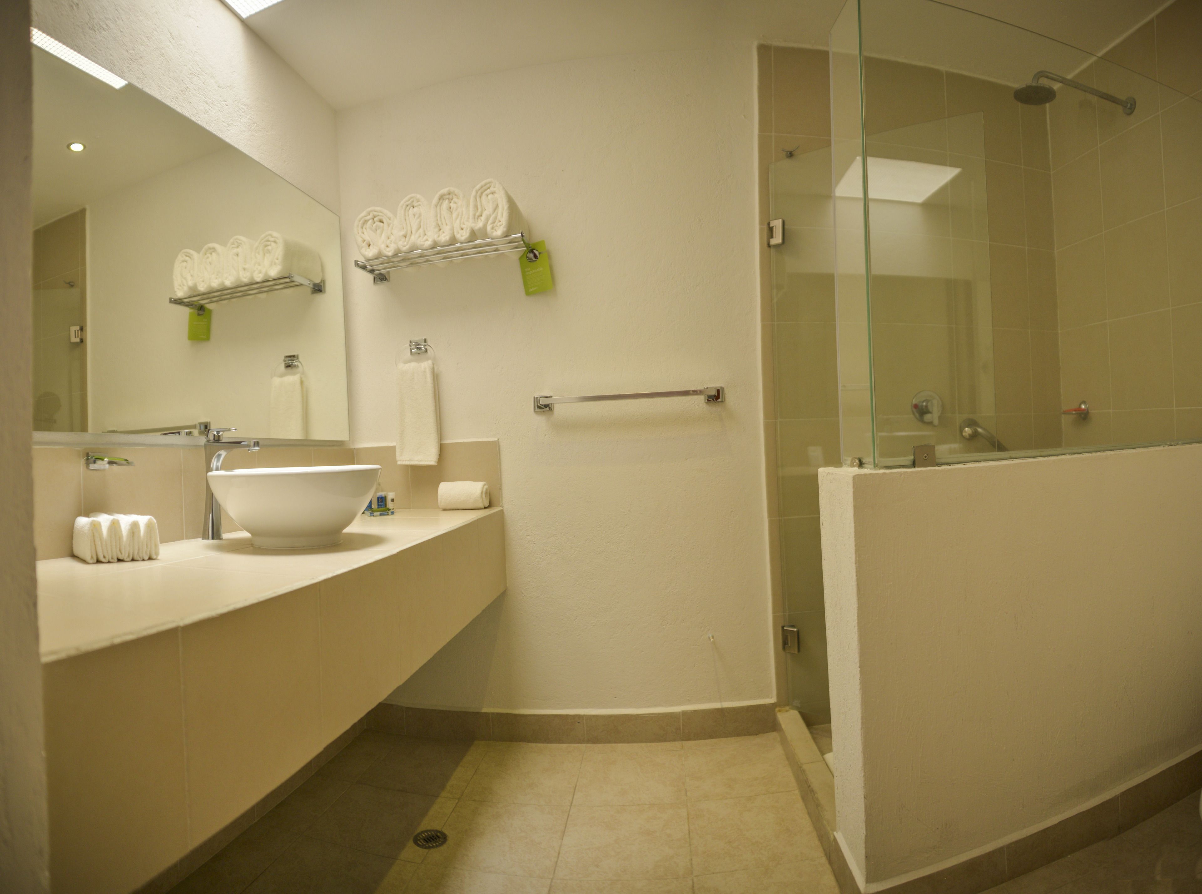 Un baño moderno con un lavabo grande, espejo y cabina de ducha de cristal.