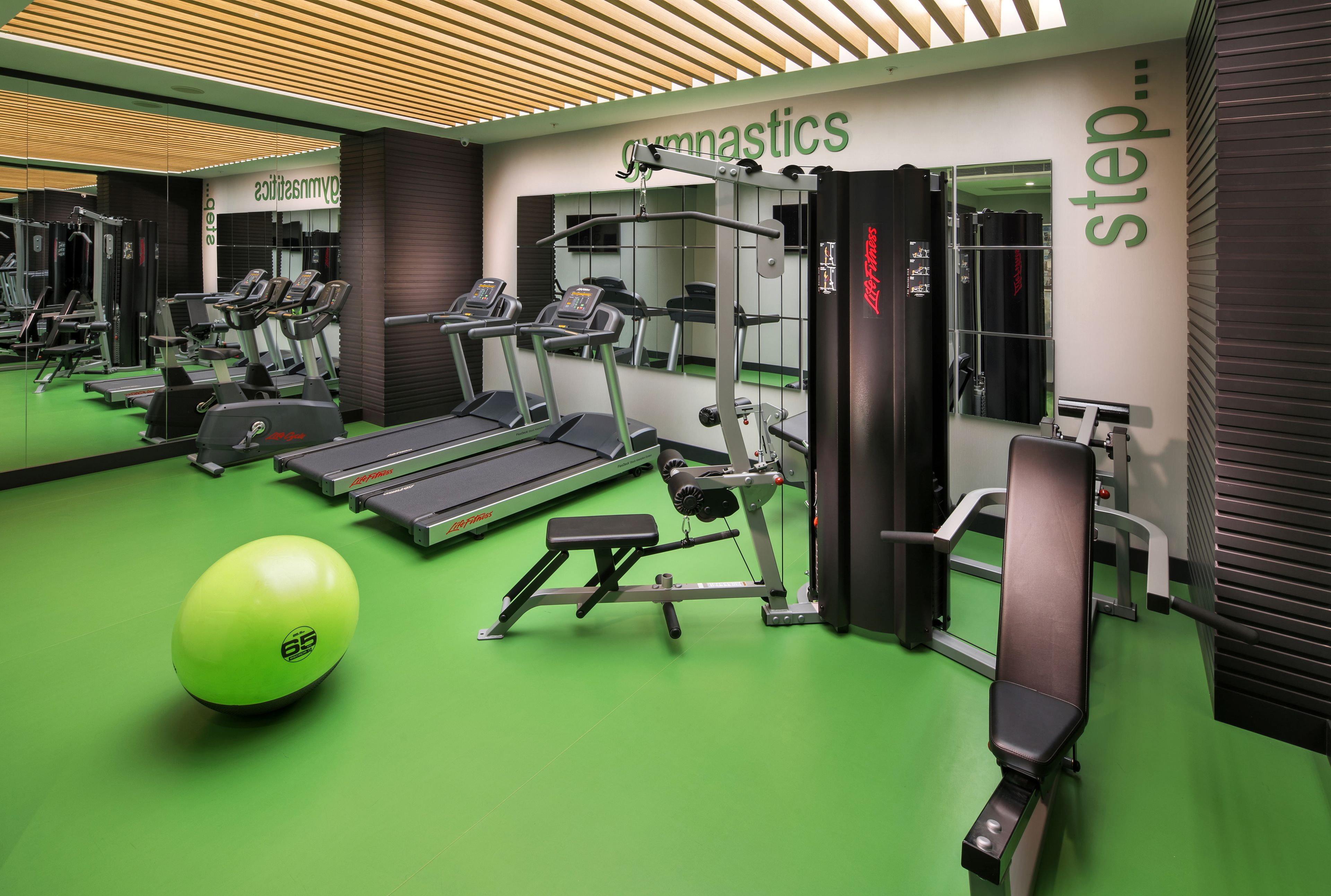 Een sportschool met loopbanden, een bankdrukrek en een medicine ball.