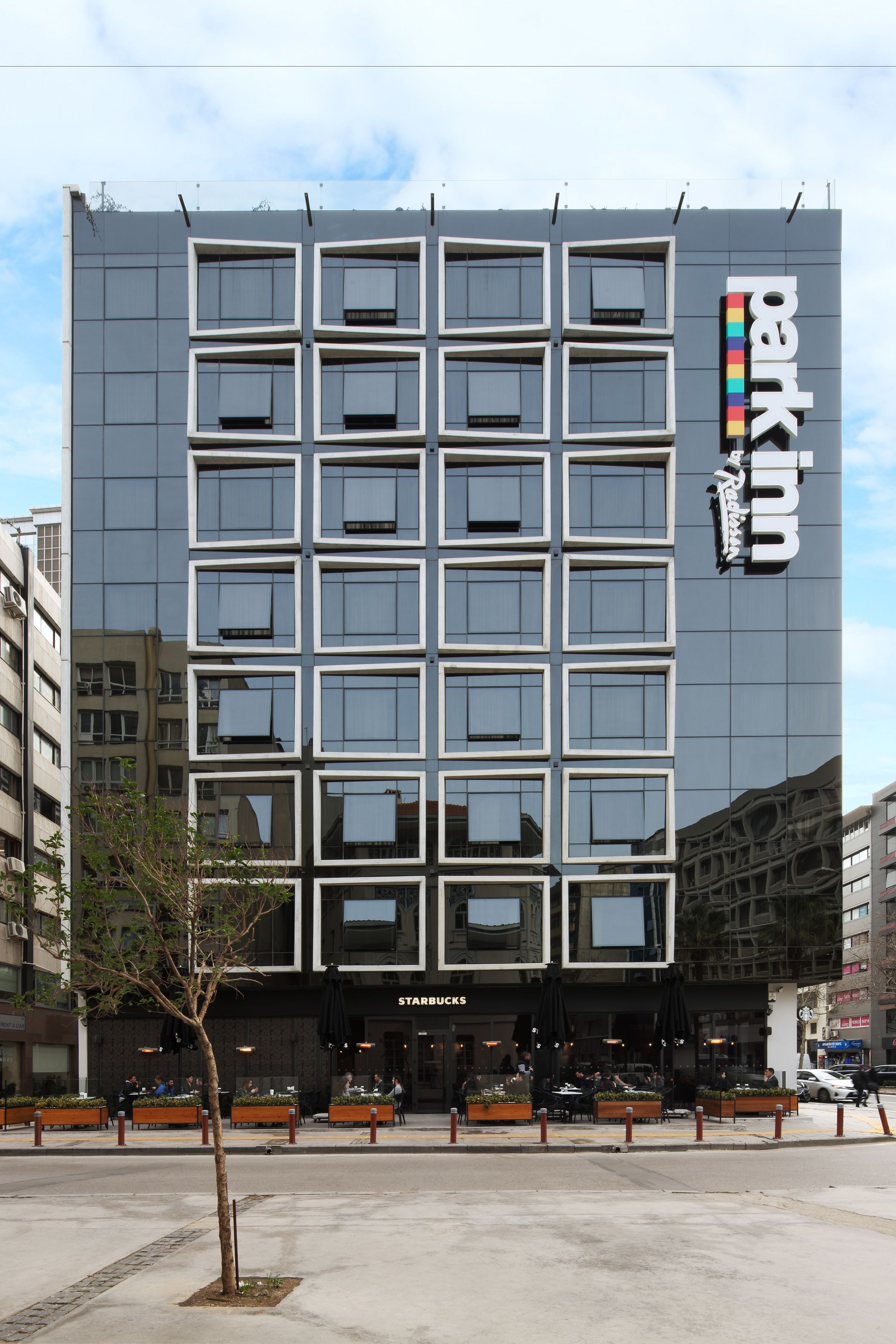A modern building with a Starbucks on the ground floor, featuring a grid of windows and a prominent sign.