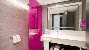 A modern bathroom with a pink shower area, a white sink with a mirror, and a towel rack.