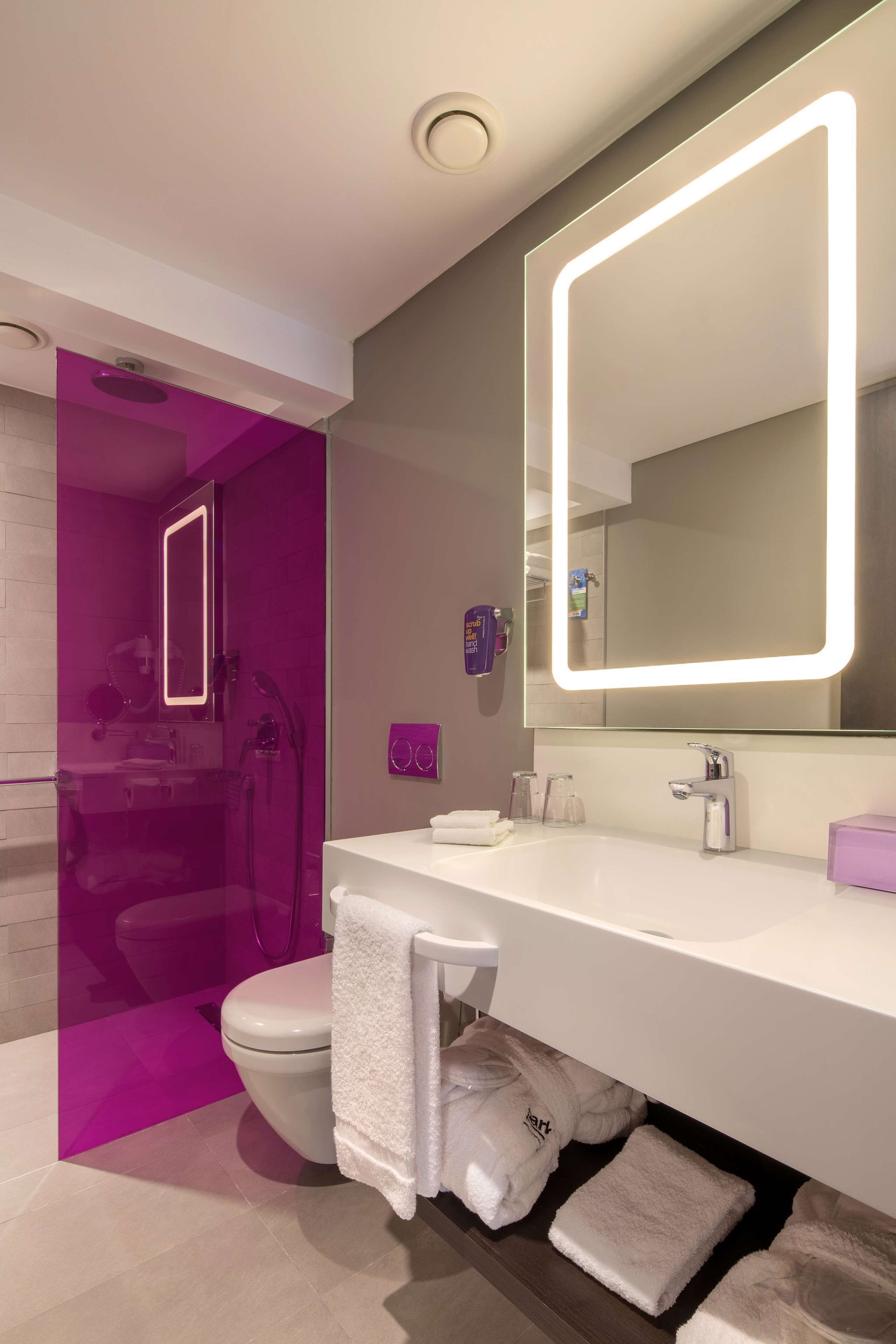 A modern bathroom with a large mirror, white sink, and a glass shower enclosure.