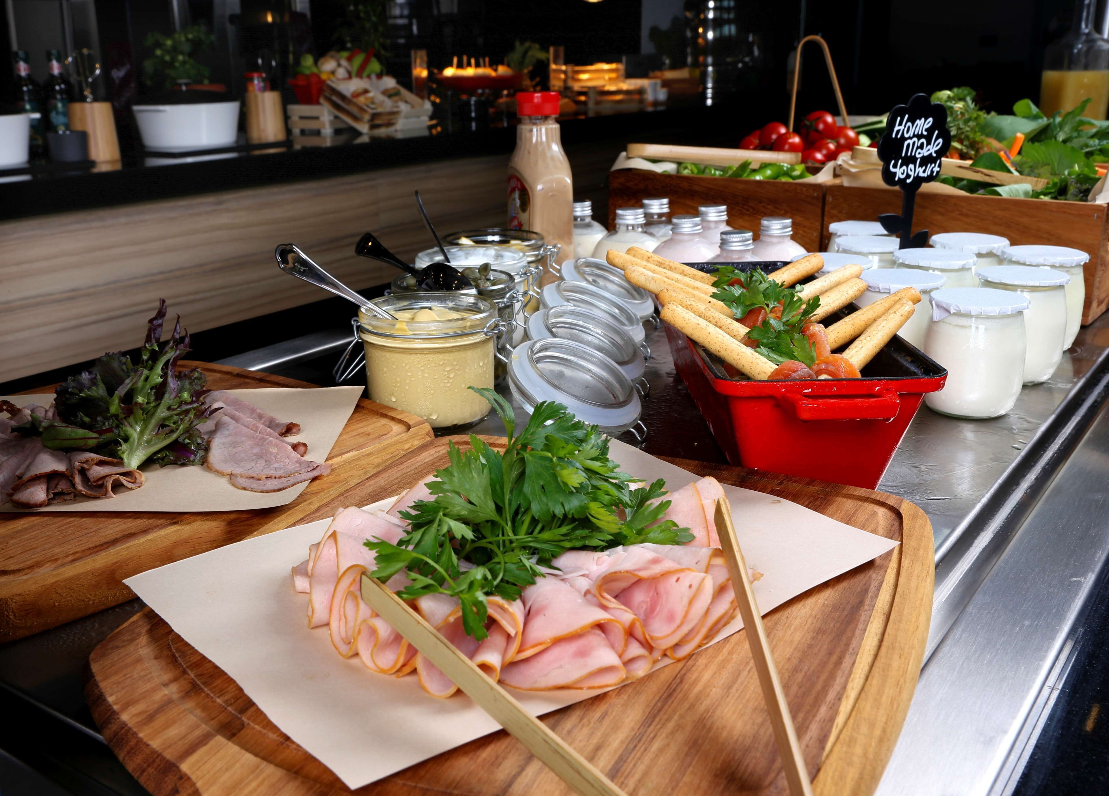 Una mesa de buffet con diversos alimentos, incluyendo fiambres, quesos y salsas.
