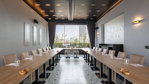 A conference room with a long table, chairs, and a view of buildings through large windows. - Park Inn by Radisson Izmir (Izmir)