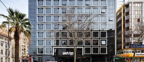 A modern building with a 'Park Inn' sign, multiple parking spaces, and a 'Starbucks' across the street.