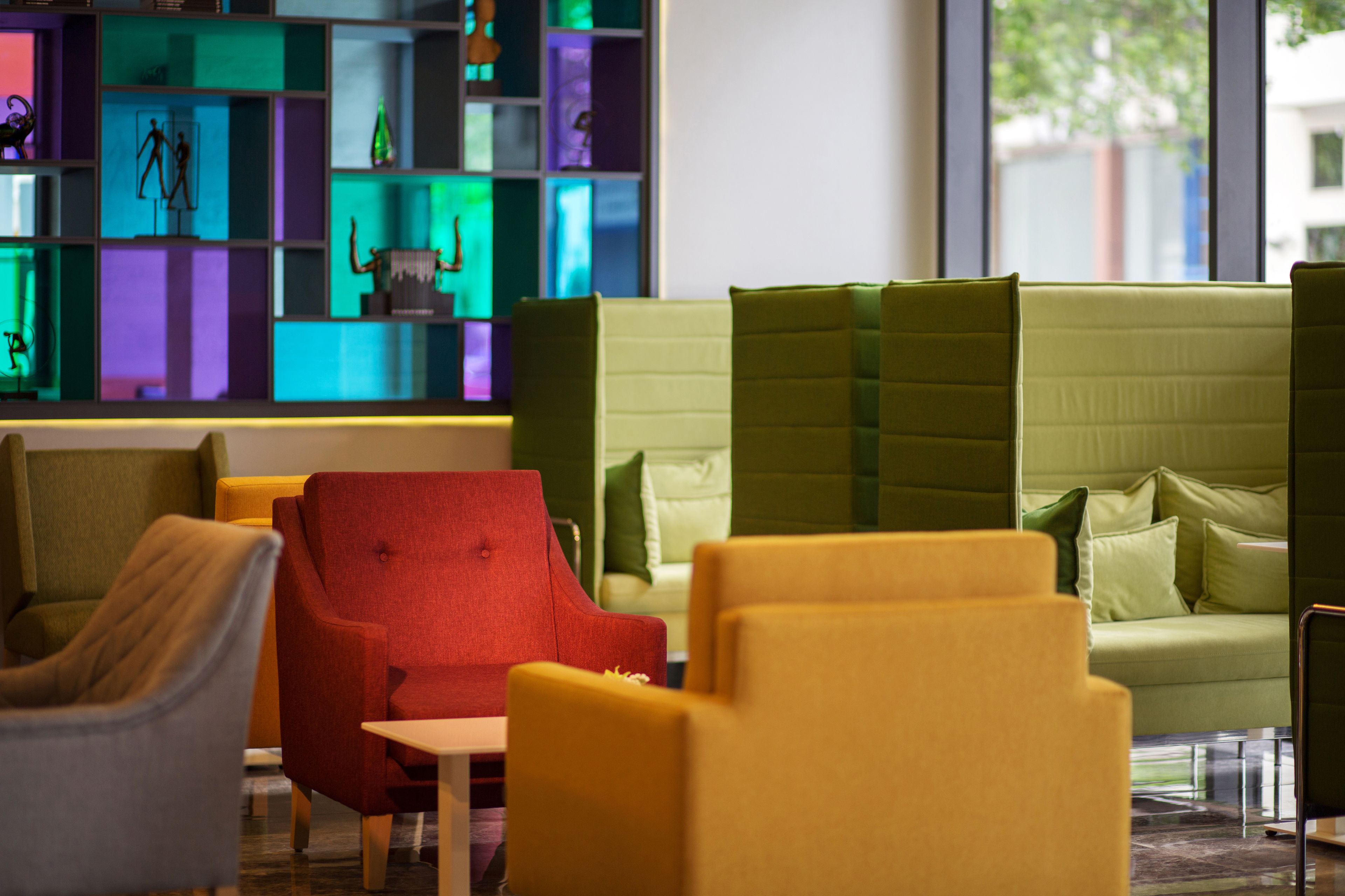 A modern interior with a green sofa, yellow armchairs, and a red armchair.