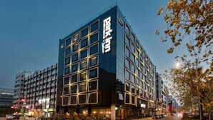 Un hôtel moderne, avec une enseigne bien visible, de nombreux étages et une façade en verre.