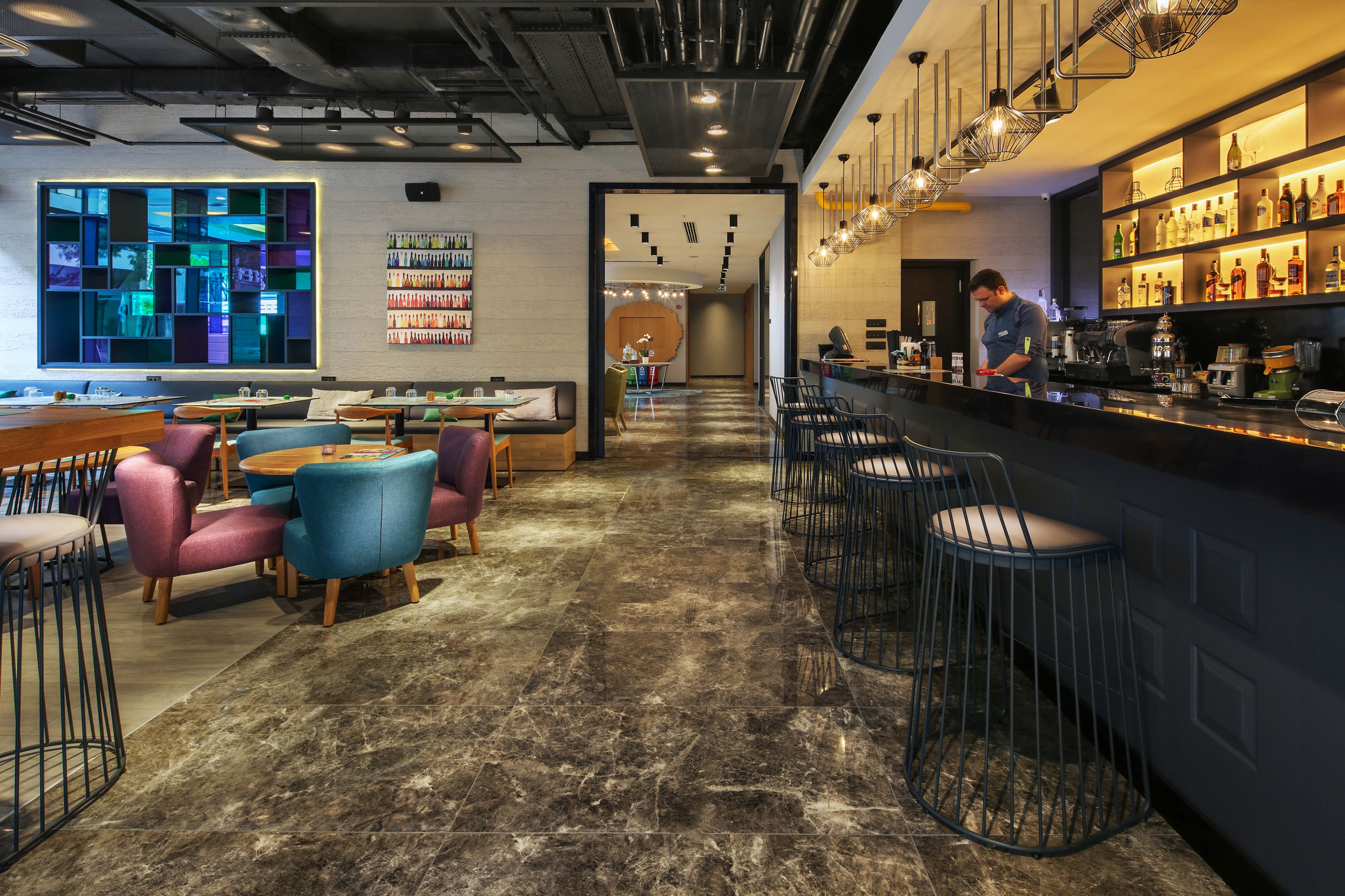 A modern bar area with seating and a bartender.