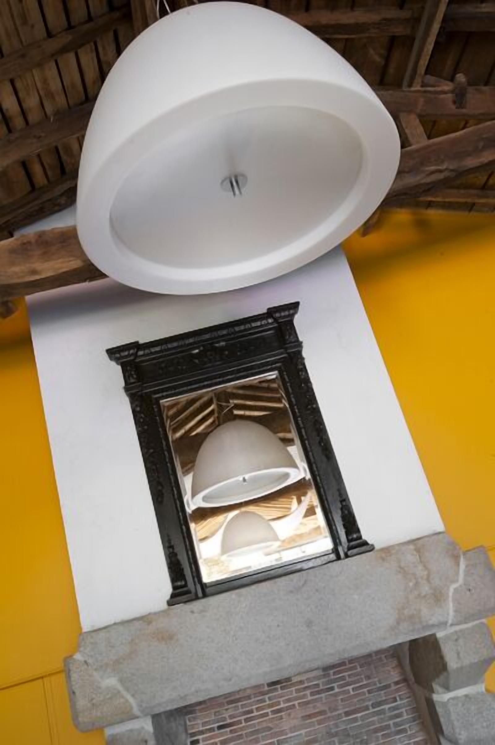 A fireplace with a stone mantel, a white ceiling light fixture, and a yellow wall.