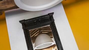 A fireplace with a stone mantel, a white ceiling light fixture, and a yellow wall.