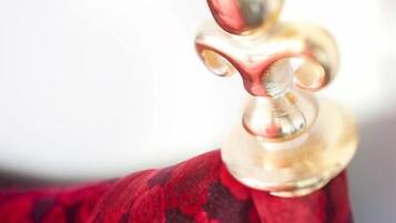 A close-up of a brass object, possibly a decorative piece, attached to a red fabric with a floral pattern.