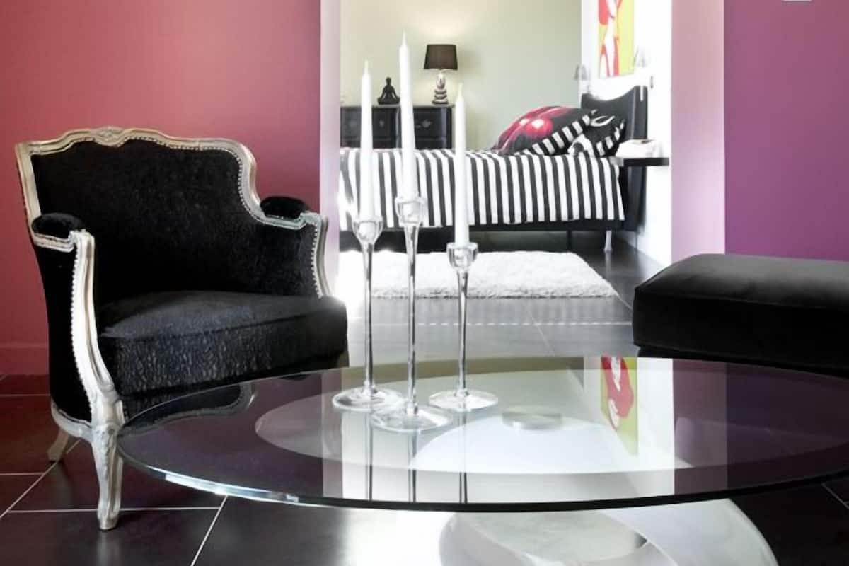 A modern living room with a round glass coffee table, a black upholstered armchair, and a striped sofa.