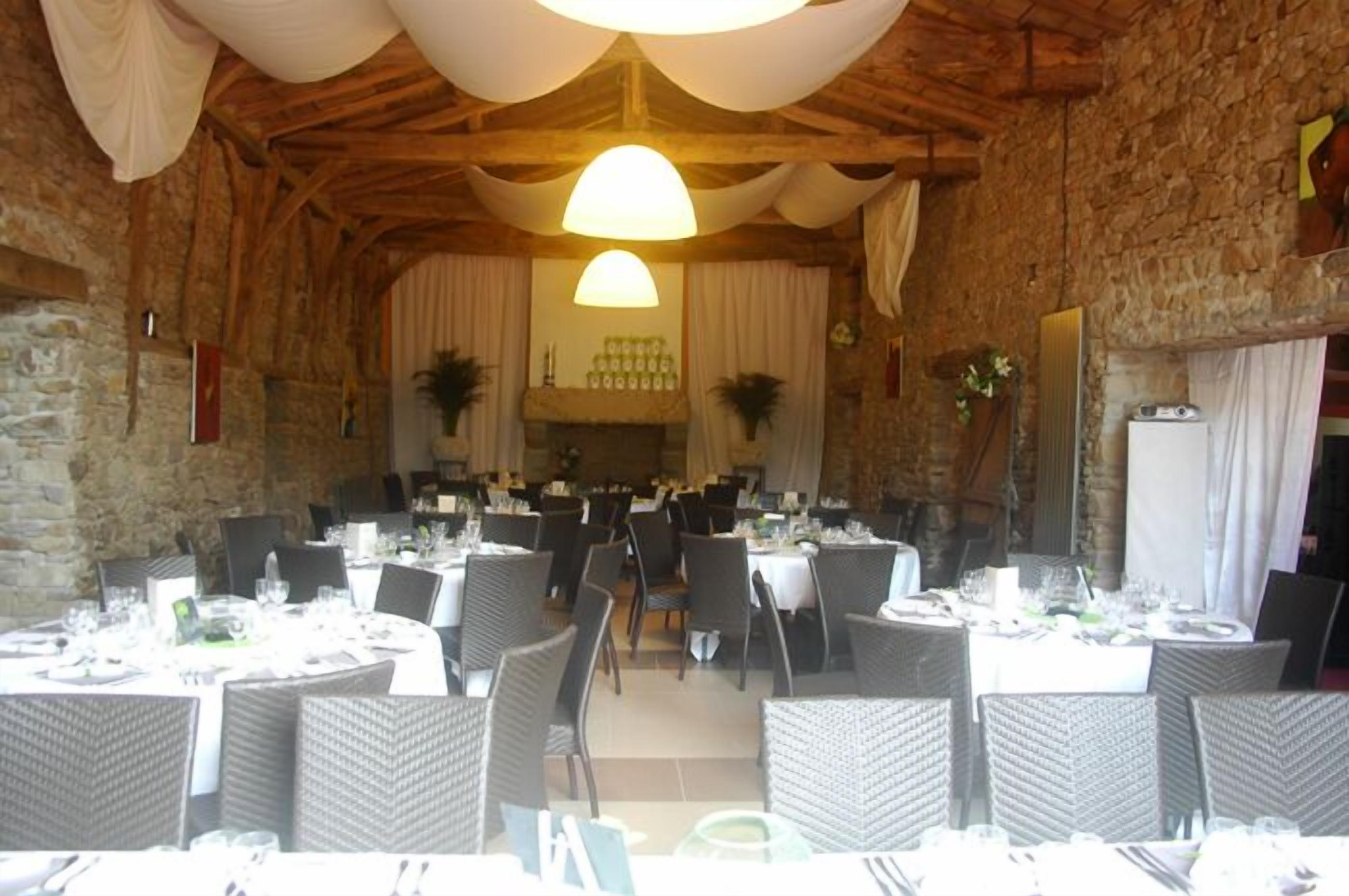 A restaurant with stone walls, round tables, and wicker chairs.