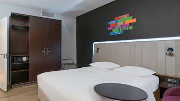 A hotel room with a bed, bedside table, and a wardrobe.