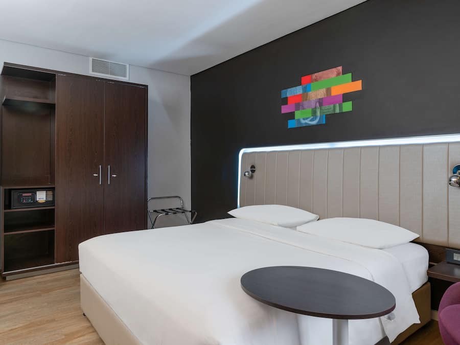 A hotel room with a bed, bedside table, and a wardrobe.