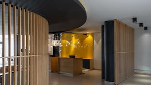 A modern reception area with a curved wooden partition, a reception desk, and a seating area.