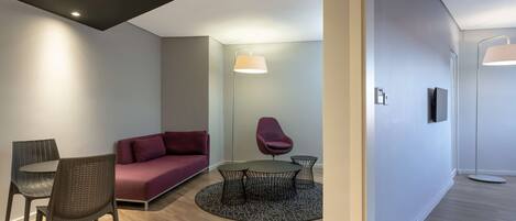 A modern living room with a round table, two chairs, a sofa, and a floor lamp.