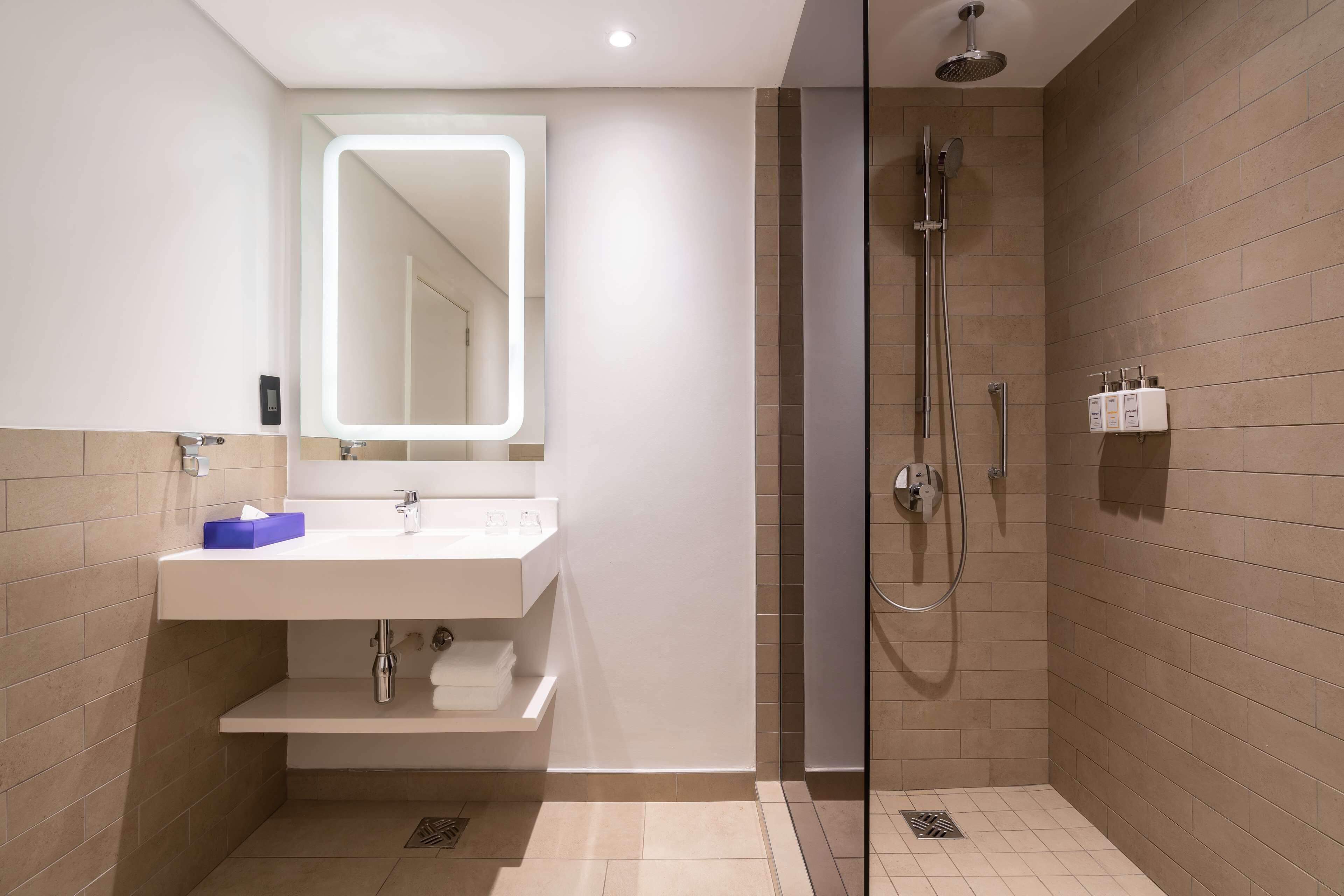 Un baño moderno con lavamanos, espejo y ducha blancos.