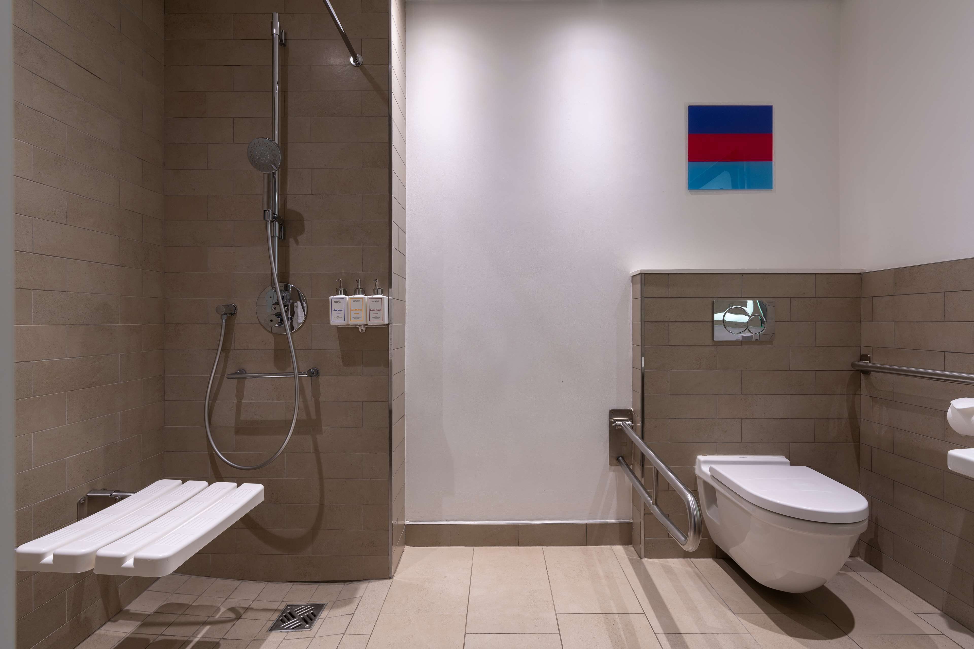 Un baño moderno con ducha, inodoro y estante.