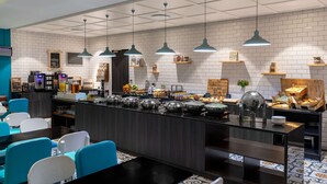 A modern cafe with a long counter, blue chairs, and a variety of food and drink items displayed.